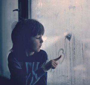 Child drawing on window humidity