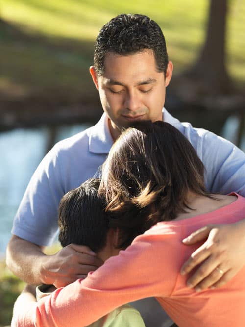 Father hugging two young children
