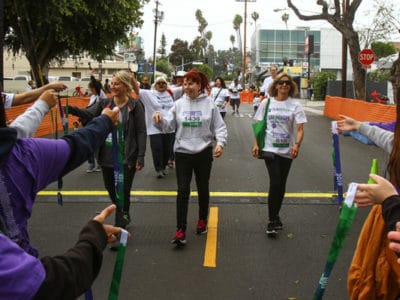 3 women crossing finish line and being handed medals