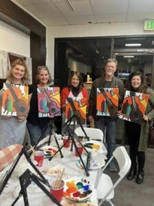 Alumni holding canvases they painted