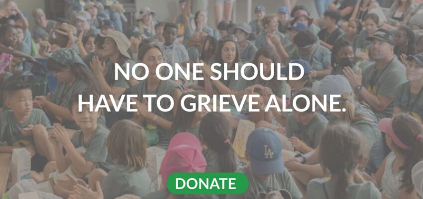 No One Should have to Grieve Alone. Donate to support Our House. Image of a group of people sitting in a row with their heads down.
