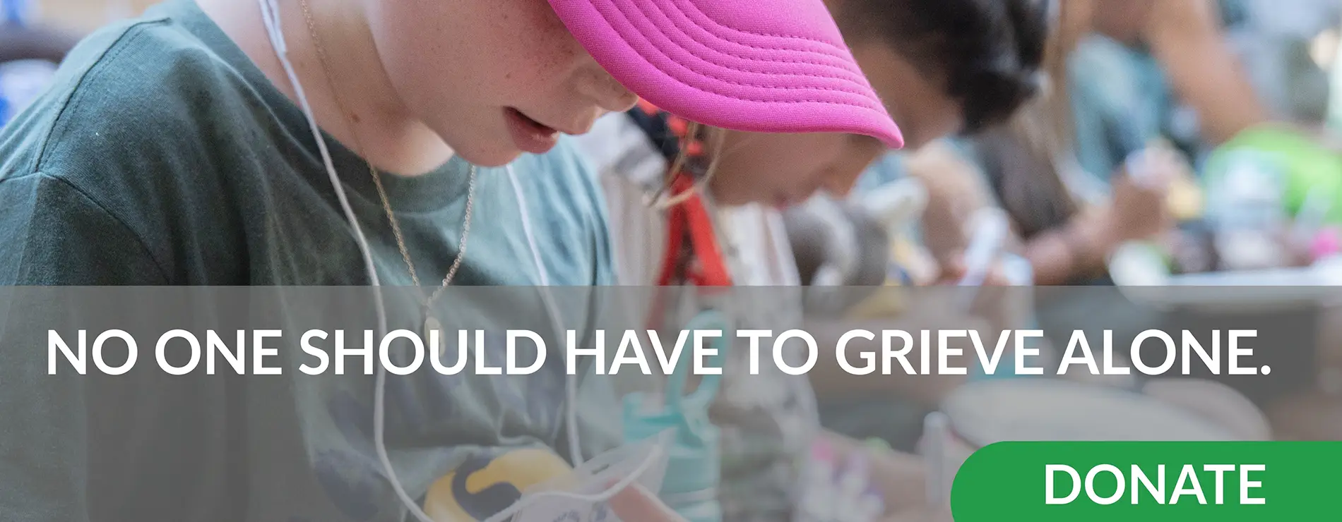 No One Should have to Grieve Alone. Donate to support Our House. Image of a group of people sitting in a row with their heads down.